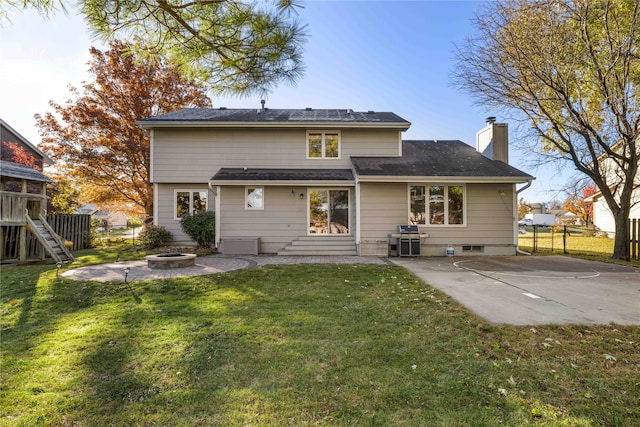 back of property featuring a yard, a patio, and a fire pit