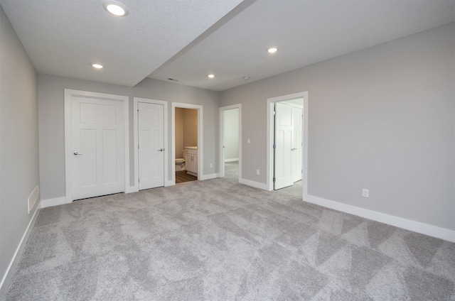 unfurnished bedroom with light carpet and ensuite bath