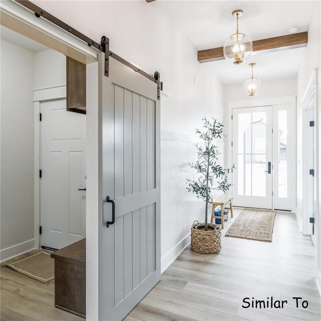 entrance foyer with light hardwood / wood-style floors, beamed ceiling, and a barn door