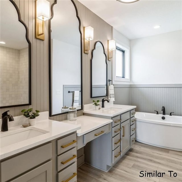 bathroom with hardwood / wood-style floors, a tub to relax in, and vanity