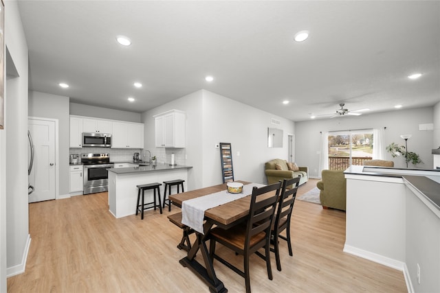 dining space featuring ceiling fan, light hardwood / wood-style flooring, and sink