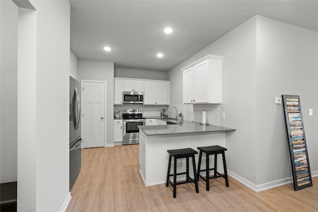 kitchen with white cabinets, kitchen peninsula, sink, and appliances with stainless steel finishes