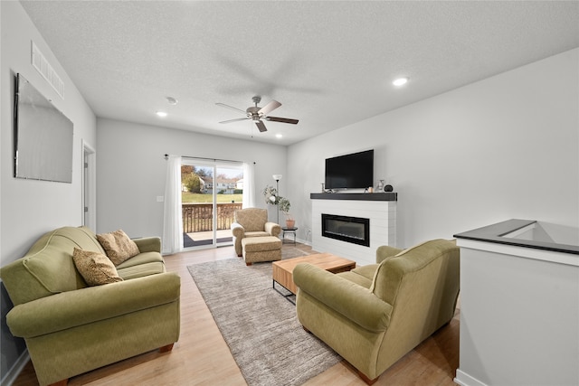 living room with hardwood / wood-style flooring, ceiling fan, and a textured ceiling