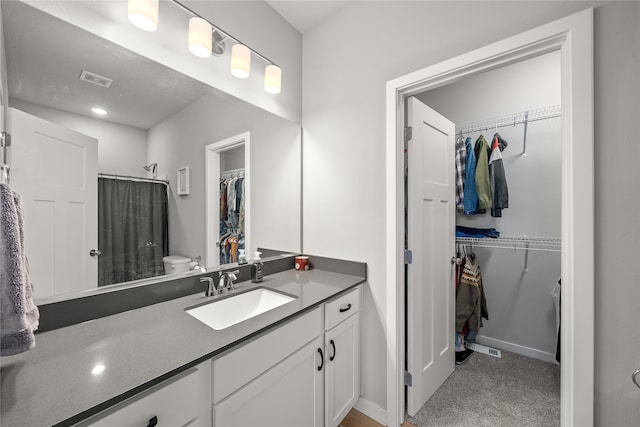 bathroom with walk in shower, vanity, and toilet