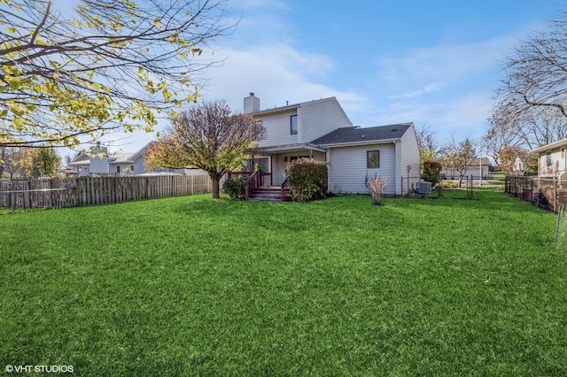 rear view of property with central air condition unit and a yard