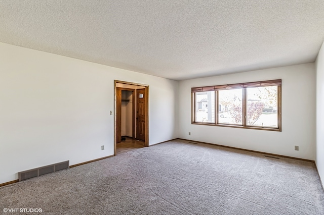 unfurnished room with a textured ceiling and carpet flooring