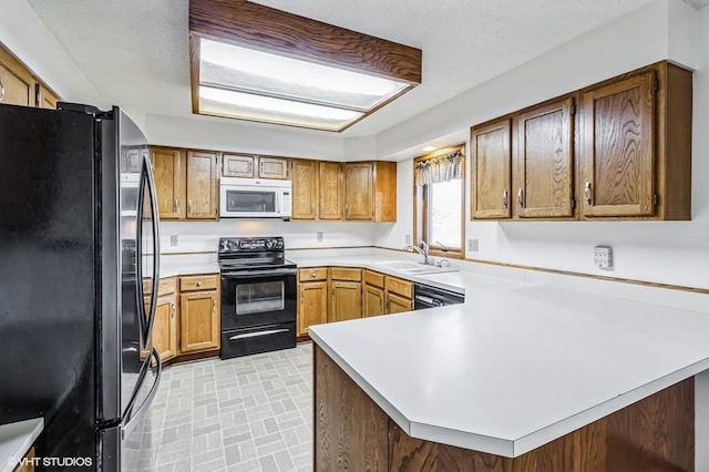 kitchen featuring a textured ceiling, sink, black appliances, and kitchen peninsula