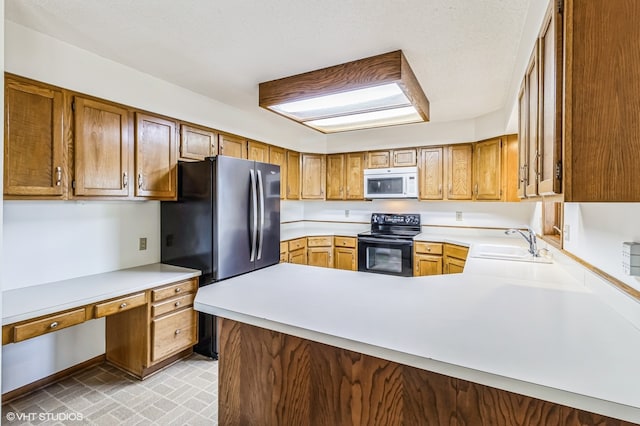 kitchen featuring black electric range, kitchen peninsula, sink, and stainless steel refrigerator