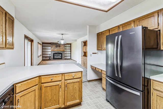 kitchen featuring a brick fireplace, kitchen peninsula, light carpet, a textured ceiling, and stainless steel fridge