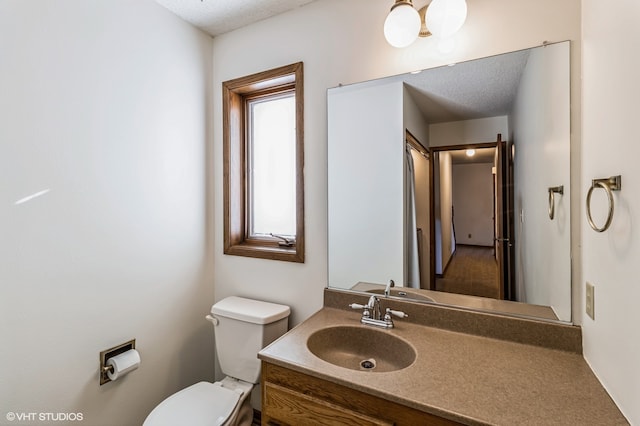 bathroom with toilet, vanity, and a textured ceiling