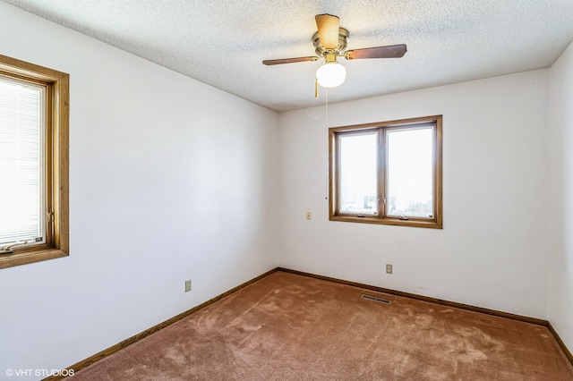 spare room with a textured ceiling, carpet flooring, and ceiling fan