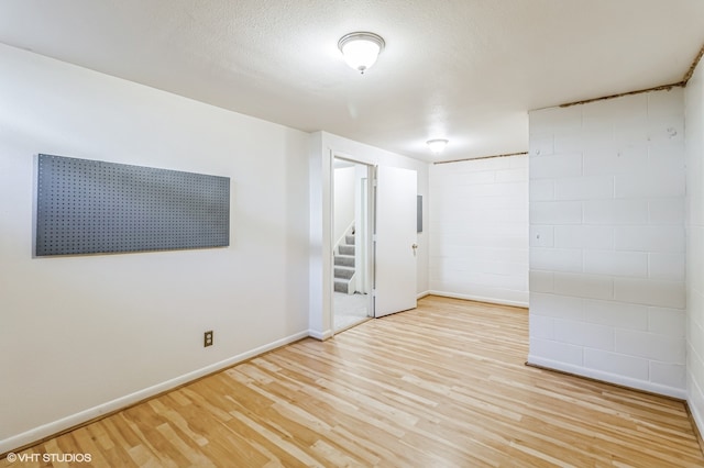 spare room with light wood-type flooring and a textured ceiling