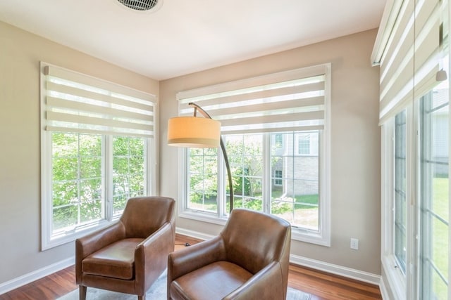 sitting room with wood finished floors, visible vents, and baseboards