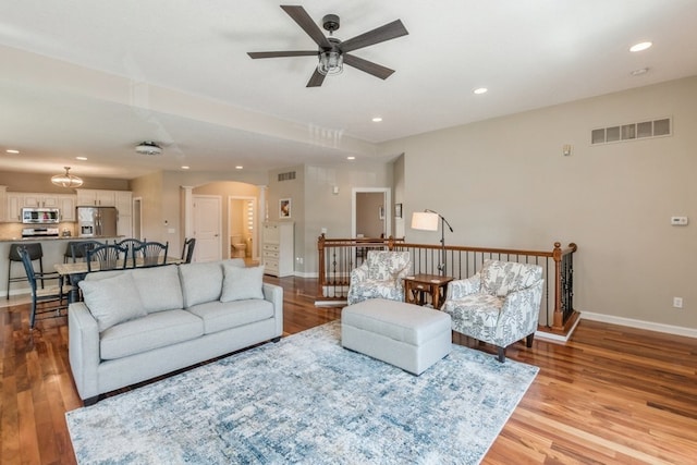 living room featuring light wood-type flooring, visible vents, arched walkways, and recessed lighting