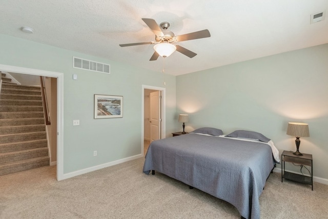 carpeted bedroom with ceiling fan, a textured ceiling, visible vents, and baseboards