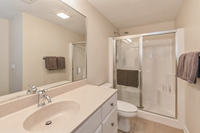 full bathroom featuring toilet, vanity, a textured ceiling, a shower stall, and tile patterned floors