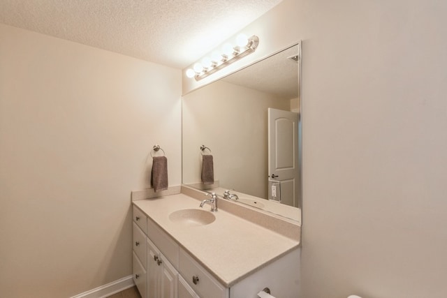 bathroom with baseboards, a textured ceiling, and vanity