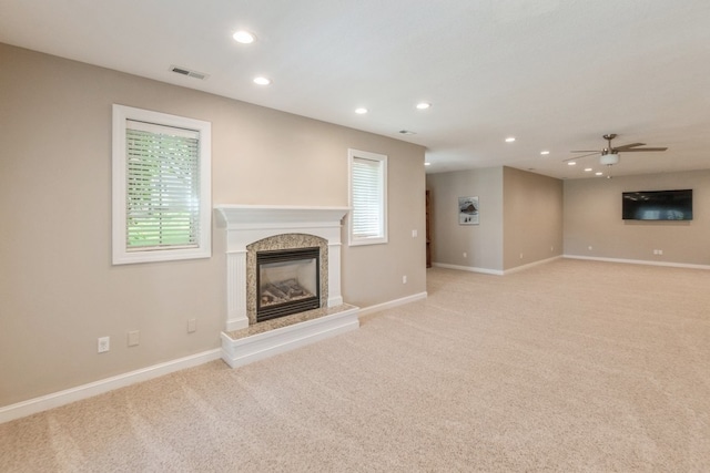 unfurnished living room featuring a fireplace, visible vents, a wealth of natural light, and light colored carpet