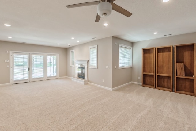 unfurnished living room with light carpet, a glass covered fireplace, and baseboards