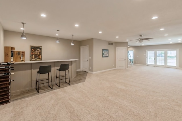 interior space with a breakfast bar area, recessed lighting, visible vents, and light colored carpet