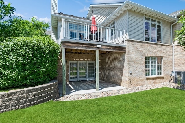 back of property with french doors, a yard, a patio area, central AC, and brick siding