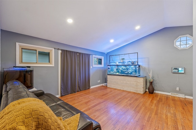 living room featuring lofted ceiling and light hardwood / wood-style floors