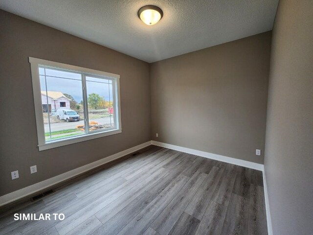 spare room featuring hardwood / wood-style floors and a textured ceiling