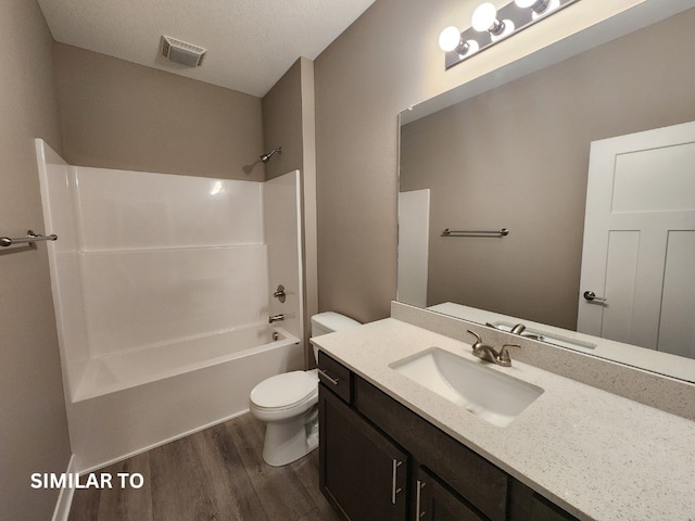 full bathroom featuring vanity, a textured ceiling,  shower combination, hardwood / wood-style flooring, and toilet