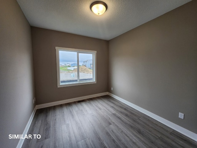 spare room with a textured ceiling and hardwood / wood-style flooring