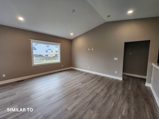 spare room with hardwood / wood-style floors and vaulted ceiling