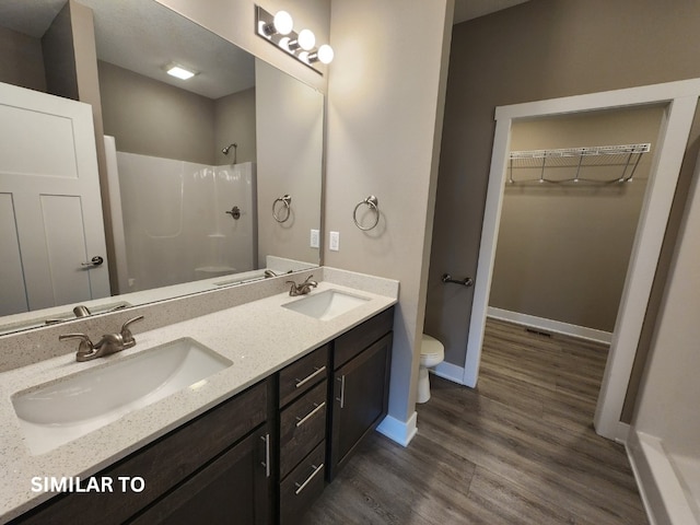 bathroom with hardwood / wood-style floors, a shower, toilet, and vanity