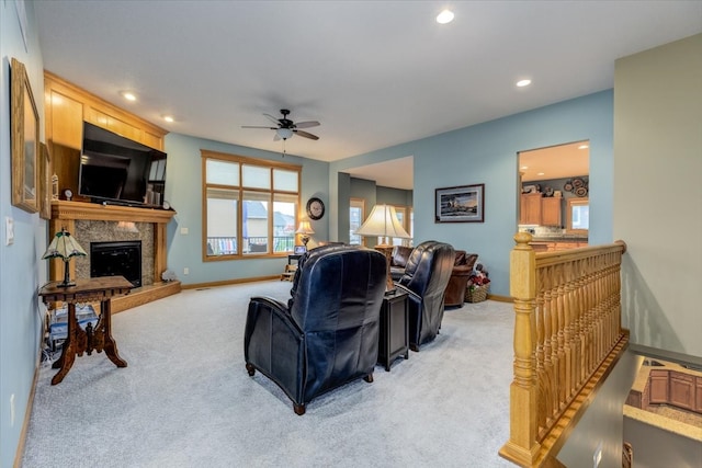 living room with a fireplace, light colored carpet, and ceiling fan