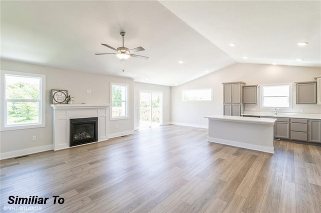 unfurnished living room featuring vaulted ceiling, ceiling fan, and light wood-type flooring