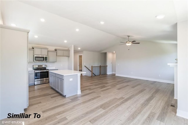 kitchen featuring gray cabinetry, a center island, stainless steel appliances, lofted ceiling, and light wood-type flooring