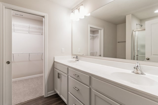 bathroom featuring double vanity, a sink, and a shower stall