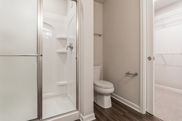 full bath featuring wood finished floors, a shower stall, toilet, and baseboards