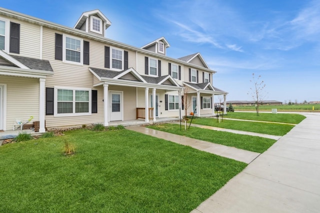 multi unit property with a shingled roof, a front yard, and covered porch