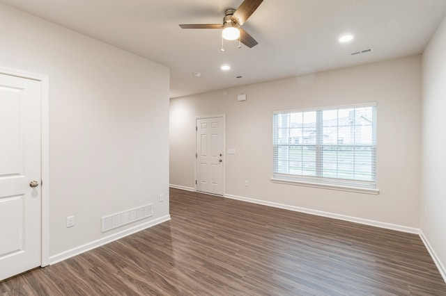 empty room featuring dark wood-style floors, baseboards, visible vents, and ceiling fan