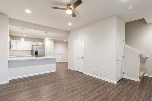 unfurnished living room with stairs, dark wood-type flooring, visible vents, and baseboards