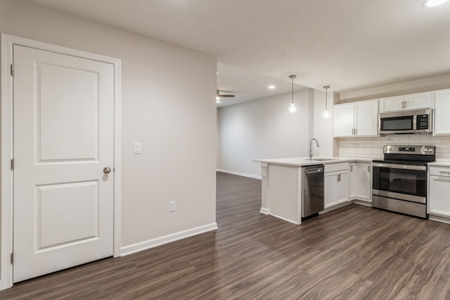 kitchen with decorative backsplash, dark wood finished floors, appliances with stainless steel finishes, a peninsula, and white cabinetry