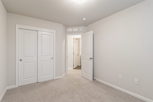 unfurnished bedroom featuring a closet, visible vents, light carpet, a textured ceiling, and baseboards