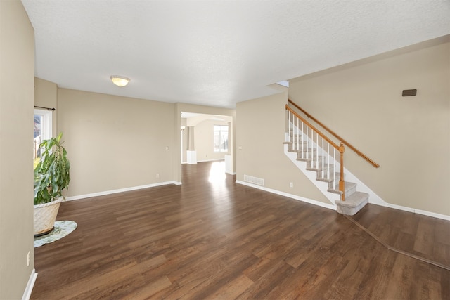 unfurnished living room with a textured ceiling, dark hardwood / wood-style flooring, and plenty of natural light