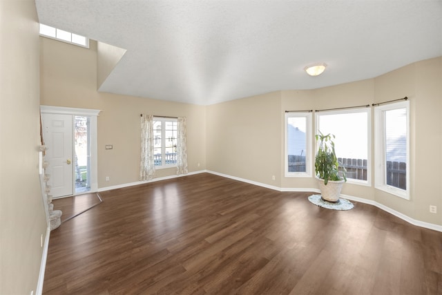 unfurnished living room featuring a textured ceiling, dark wood-type flooring, and a healthy amount of sunlight