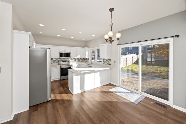 kitchen with dark hardwood / wood-style flooring, white cabinetry, hanging light fixtures, and stainless steel appliances