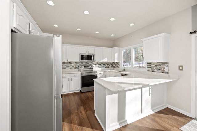 kitchen featuring kitchen peninsula, appliances with stainless steel finishes, white cabinetry, and dark wood-type flooring