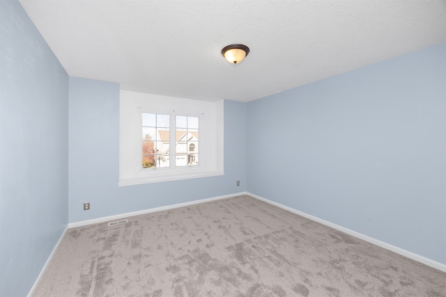 empty room featuring light carpet and a textured ceiling