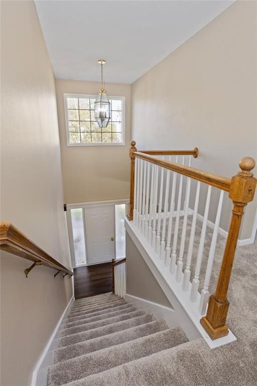 staircase featuring carpet and a chandelier