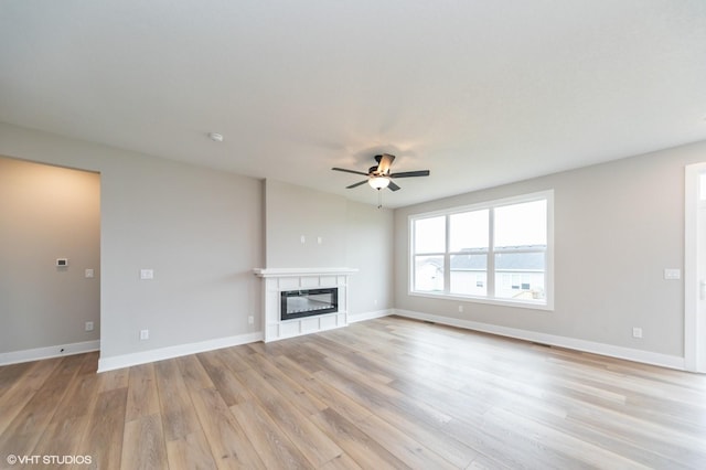2806 22nd St SW, Altoona, IA 50009 - unfurnished living room featuring light wood finished floors, ceiling fan, a glass covered fireplace, and baseboards