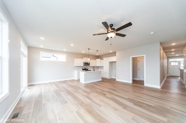 2806 22nd St SW, Altoona, IA 50009 - unfurnished living room with light wood-type flooring, a ceiling fan, recessed lighting, a sink, and baseboards