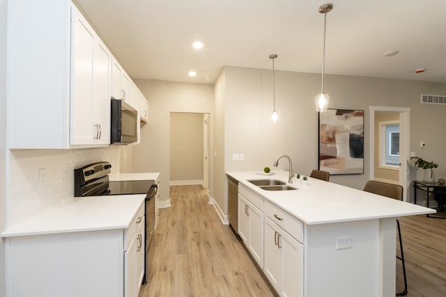 kitchen with white cabinets, pendant lighting, electric range, and sink